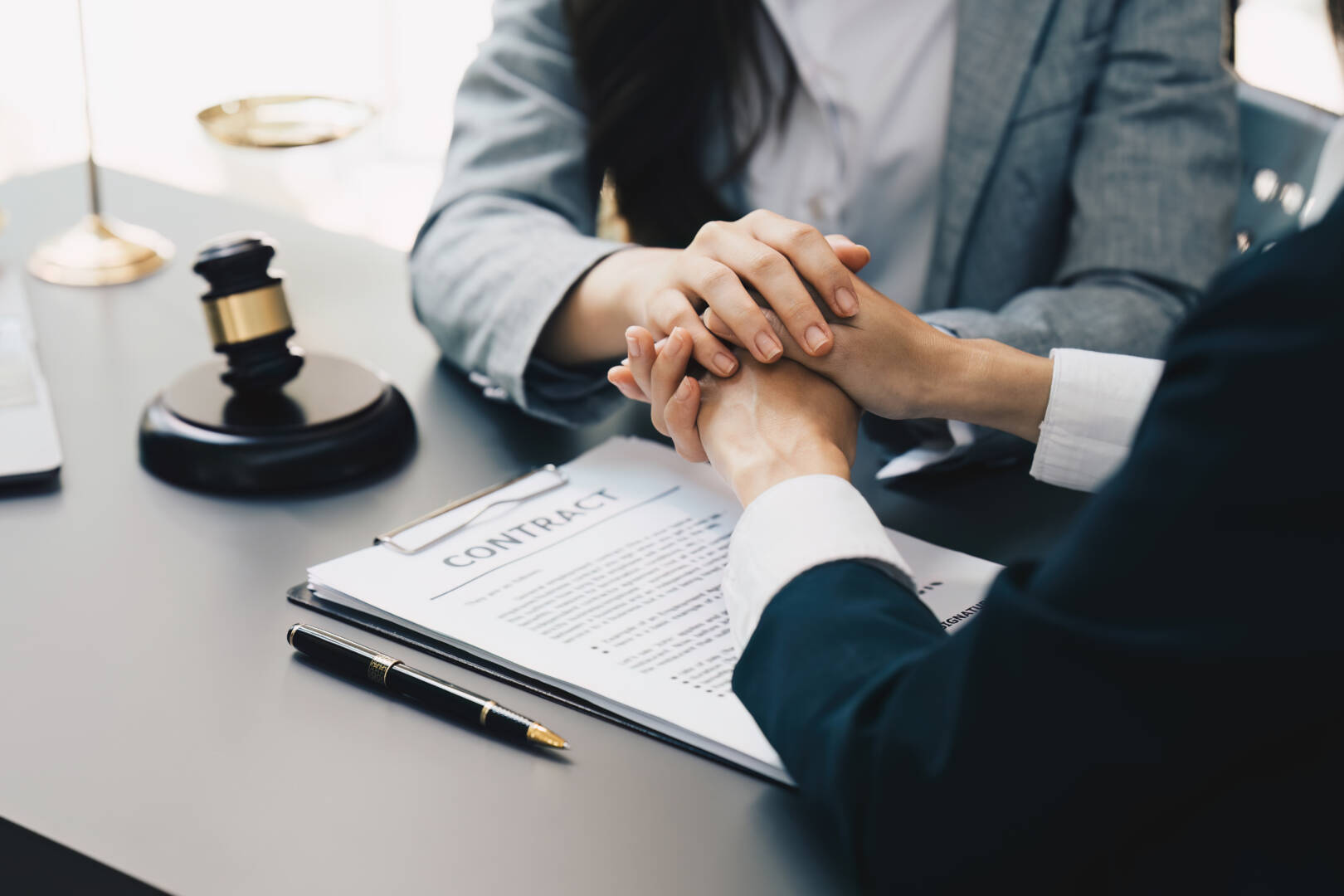 Lawyers holding business woman hand while consult at lawyer office. Law, legal services, advice, Justice and real estate concept.