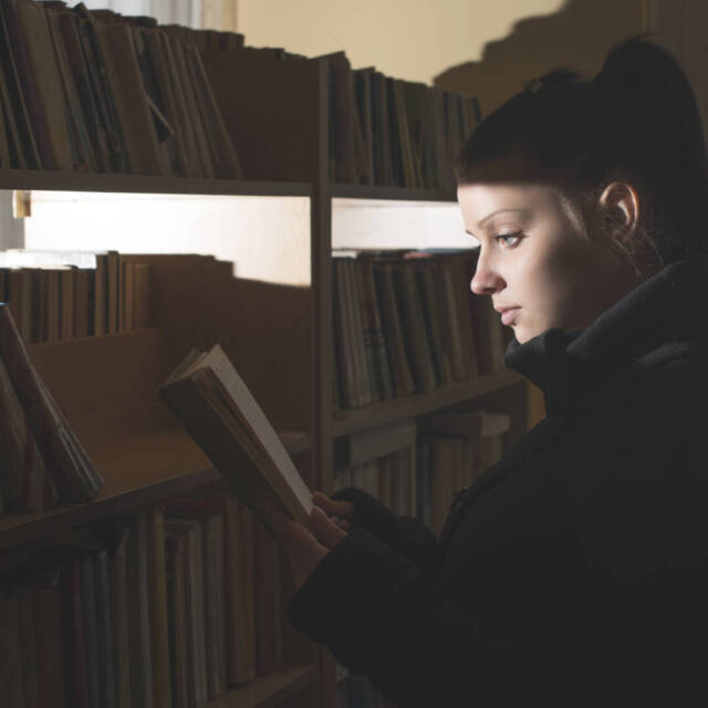 Female student reading book in a library